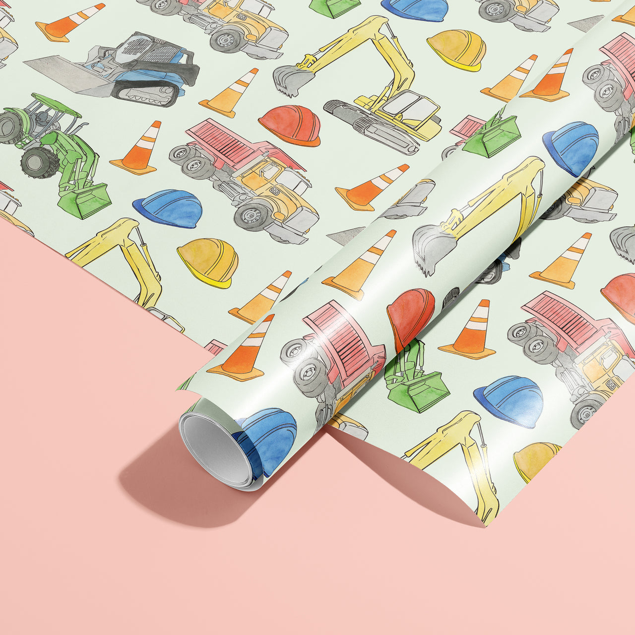 Roll of construction-themed wrapping paper with colorful trucks, cones, and hats on a light blue background.